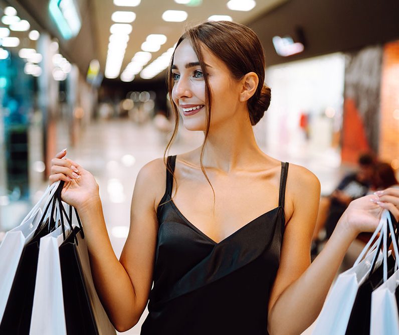 Elegant brunette woman in black dress enjoying shopping in the m
